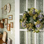 Sage dainty floral wallpaper on an office wall with vintage picture frames and beautiful floral wreath.