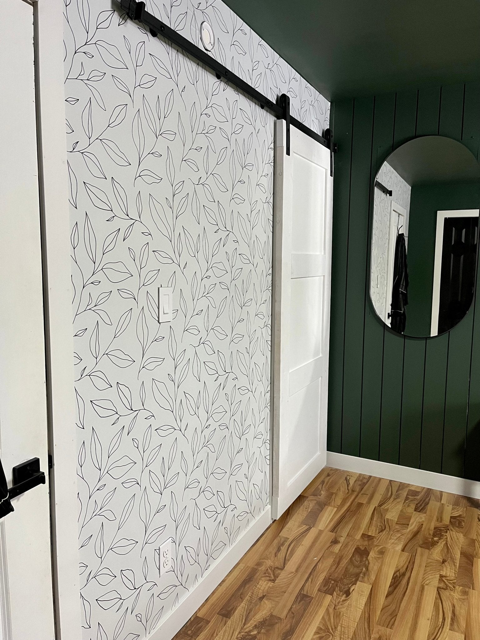 Minimal floral peel and stick wallpaper in bedroom with green walls and natural wood flooring