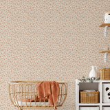 Boho nursery with removable wallpaper, decorated with orange and green floral print.