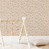 Crib against orange and green flower boho wallpaper with canopy and plush toys.