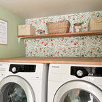 Laundry room with natural wood shelving and orange leafy peel and stick wallpaper