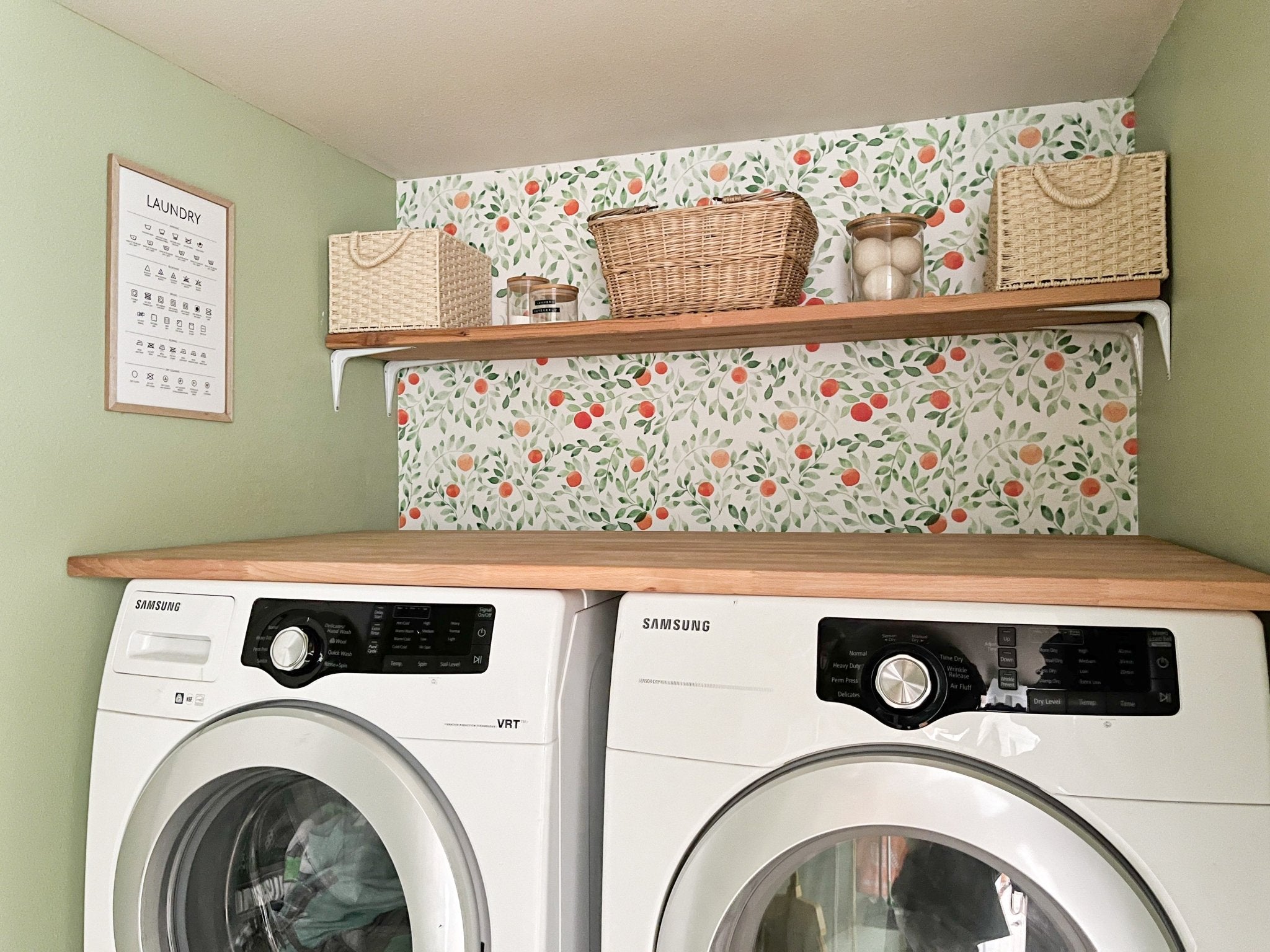 Laundry room with natural wood shelving and orange leafy peel and stick wallpaper
