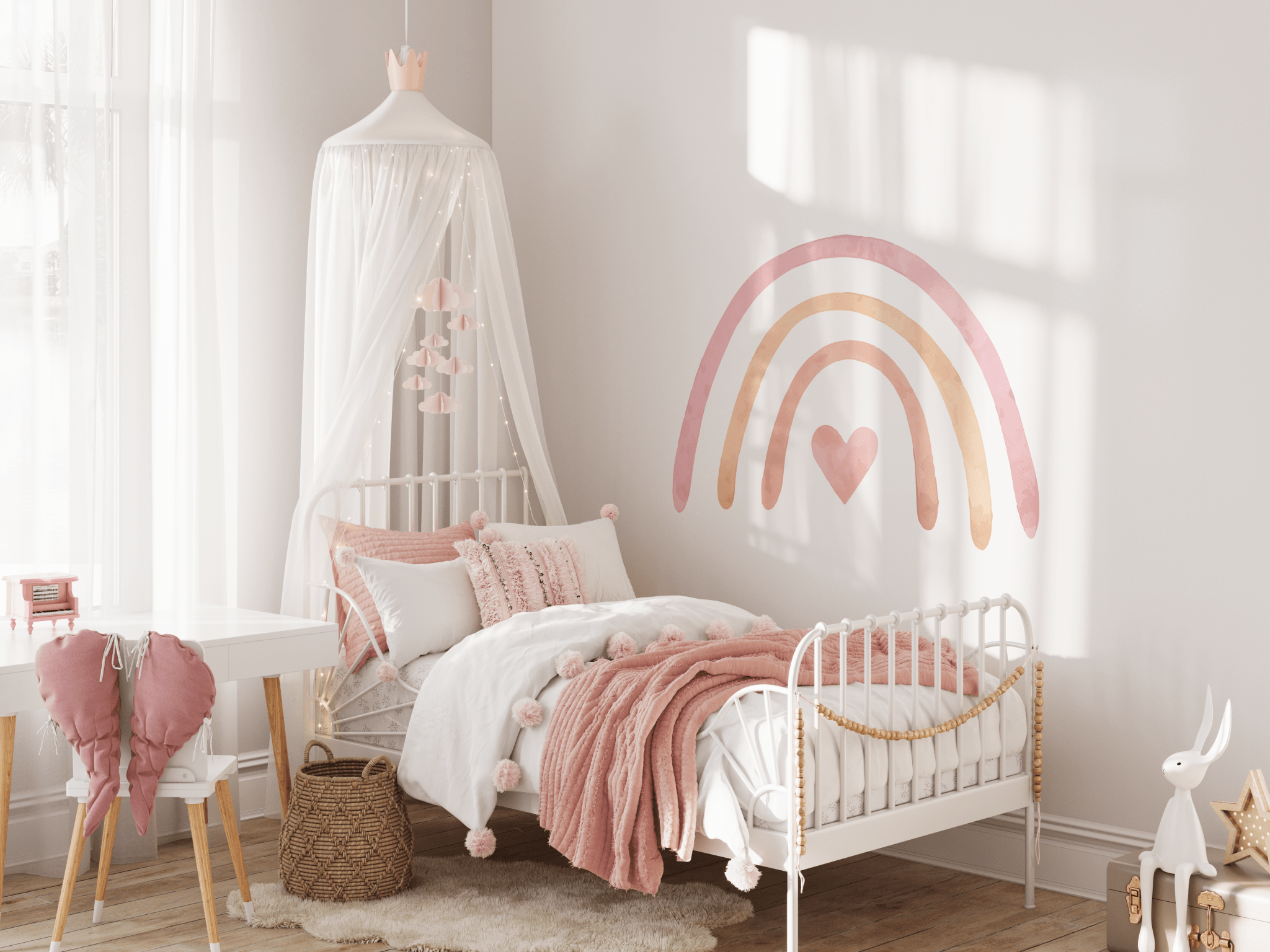 A cozy corner of a child's bedroom featuring a pastel rainbow wall decal. The room includes a white canopy over a single bed with pink bedding, a fluffy white rug on the floor, and a small wooden desk with a red chair.