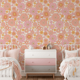 Charming children's bedroom with retro floral peel and stick wallpaper in shades of pink and orange, complemented by white and pink bedding and a stylish ombre dresser.