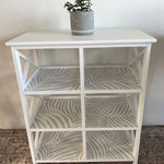 This photo shows a white open faced shelf with grey and white Scandinavian style wallpaper lining each shelf.