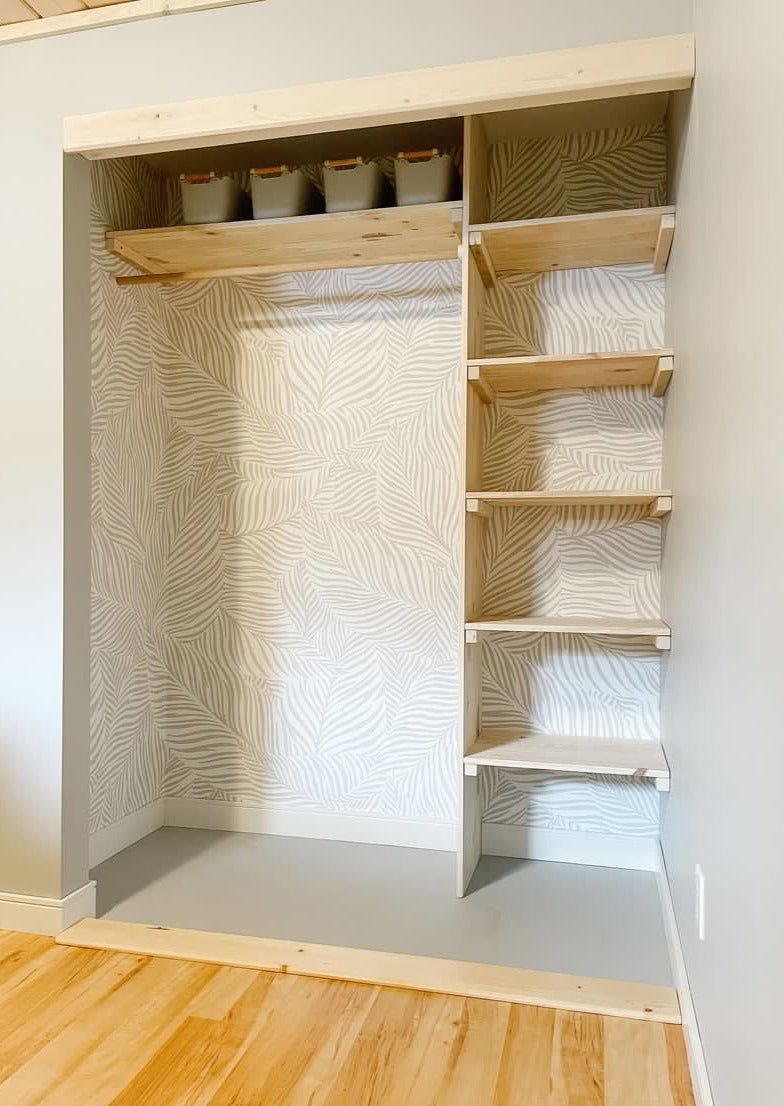 Bedroom closet renovated using natural would accents over a grey and white Scandinavian style peel and still wallpaper