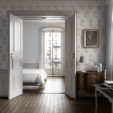 A bedroom with sketched twig peel and stick wallpaper, white bedding, and traditional wooden furniture