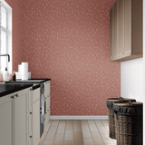 A modern laundry room with a bold terracotta dainty floral wallpaper, contrasting with white cabinets, black countertops, and wicker laundry baskets.