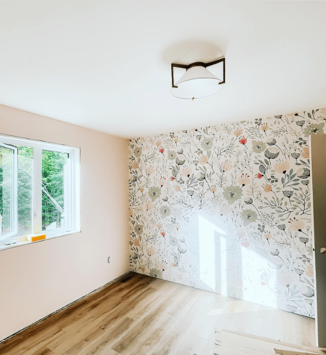 Empty room with floral wallpaper and hardwood floor before furniture arrangement."