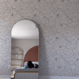 "Modern bedroom with neutral wildflower wallpaper, arch mirror, and white fluffy rug