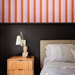 Moody modern bedroom with half-wall Taffy wallpaper above black paneling