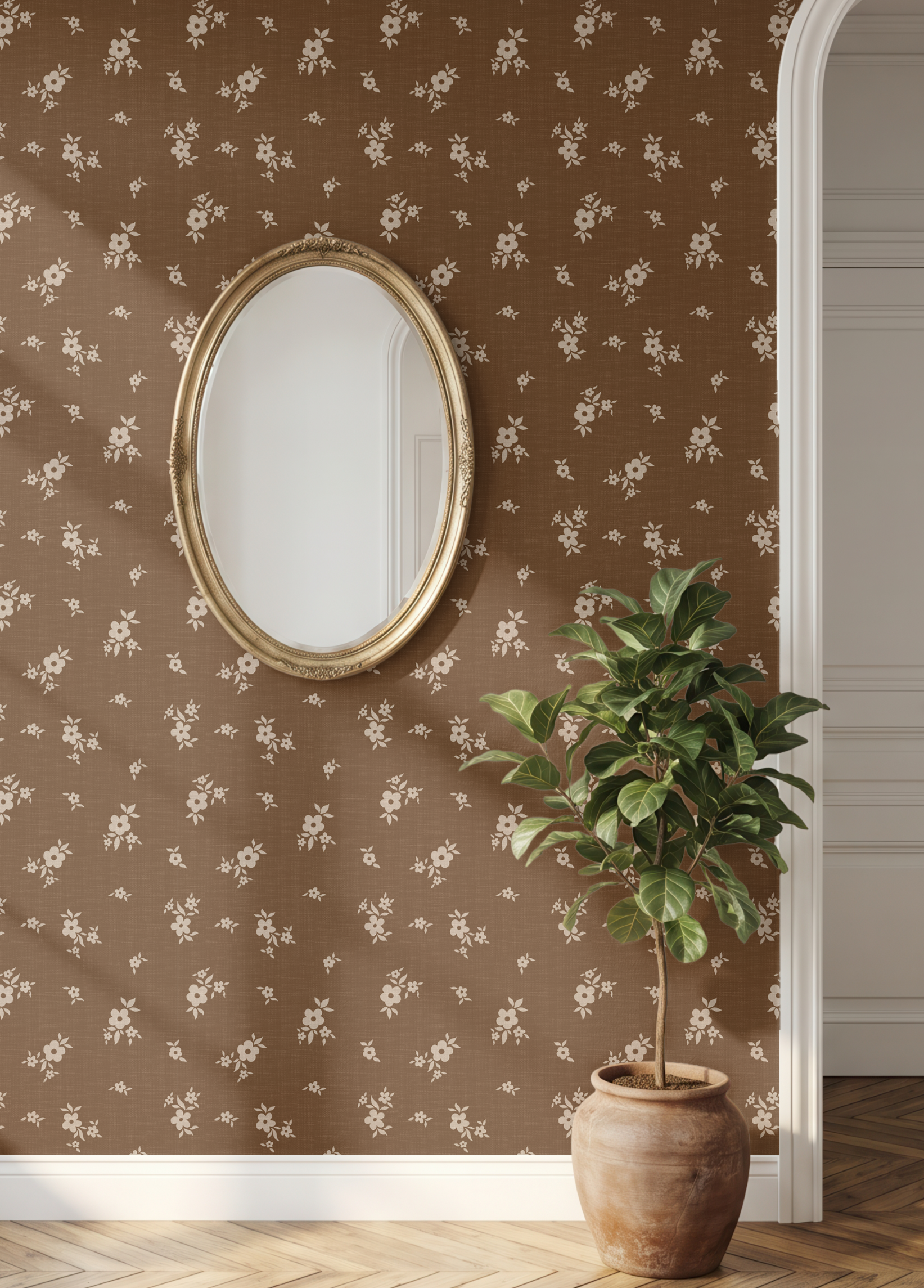 Brown floral wallpaper with a delicate white repeating pattern, styled in an interior setting with an oval gold-framed mirror and a potted green plant on a herringbone wood floor.