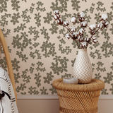 Vase with cotton branches on a woven stool against floral wallpaper
