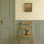 Muted green and yellow wallpaper with vintage chair and panel moulding