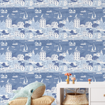 Seaside sailboat wallpaper in blue tones styled in kids playroom with wicker basket and plush whale