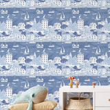 Seaside sailboat wallpaper in blue tones styled in kids playroom with wicker basket and plush whale