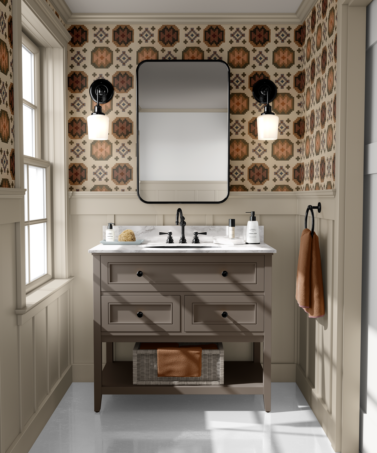 A bathroom vanity in a warm beige wood finish, set against a wall with brown and beige patterned wallpaper and black sconces. A large black-framed mirror hangs above the sink, flanked by two black wall-mounted sconces.