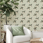 Living room corner with flying duck wallpaper, white armchair, and green pillow