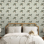 Bedroom with flying duck wallpaper behind rattan headboard and neutral bedding