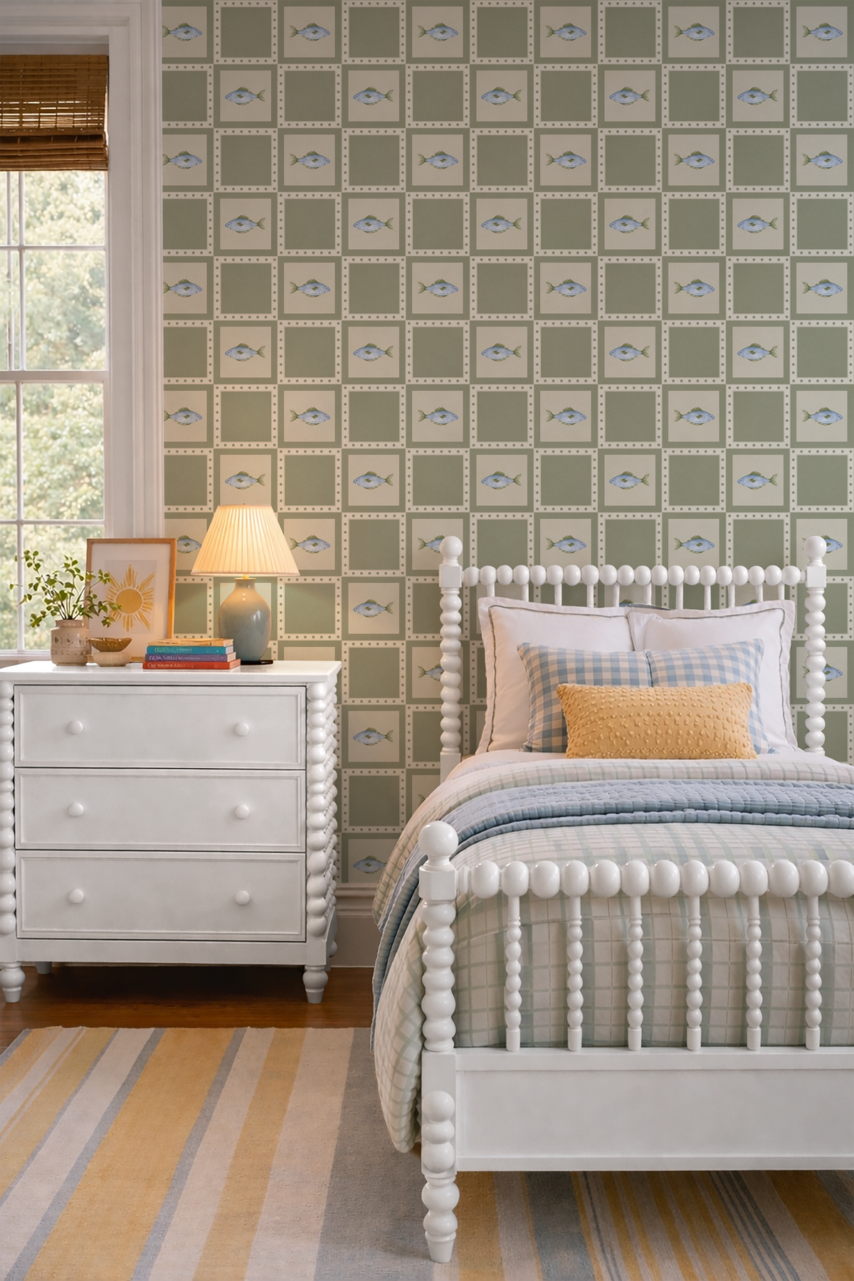 Blue fish and green patchwork wallpaper in a coastal inspired kids bedroom with white spindle bed, blue gingham bedding and warm yellow accents.