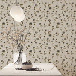 Decorative wall with floral pattern, table with vase and branches, and hanging light fixture.
