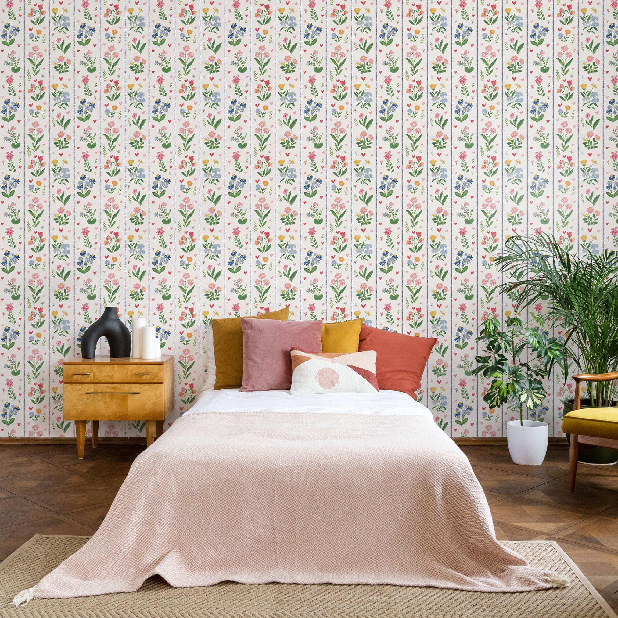 Vintage floral stripe wallpaper behind bed with pink, blue and yellow botanical pattern in cozy bedroom