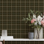 Plaid wallpaper with a vase of flowers and books on a table