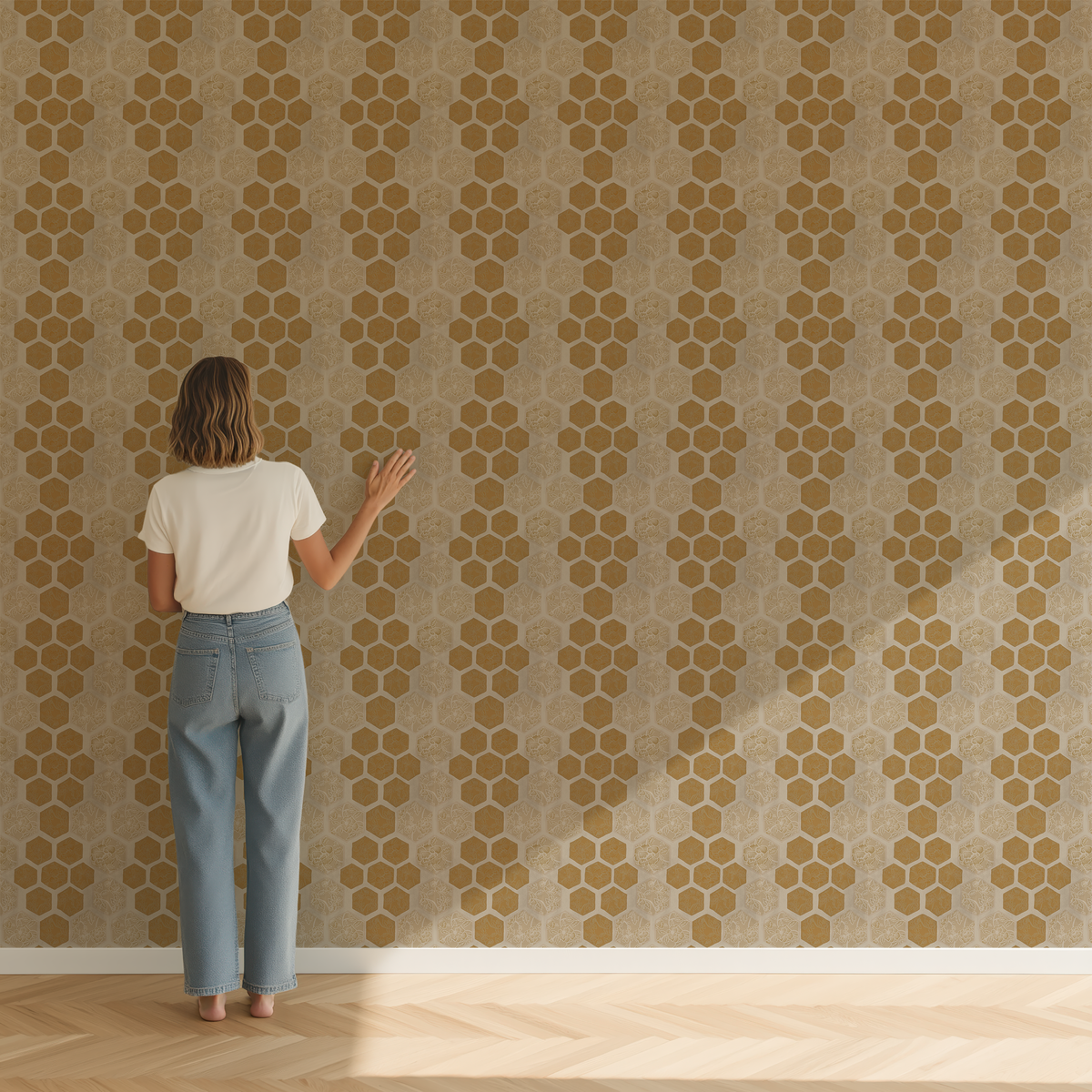 A woman stands with her back to the camera in a room, touching a wall covered in vertical honeycomb-style wallpaper in warm beige and brown tones, with light wood flooring and a white baseboard.