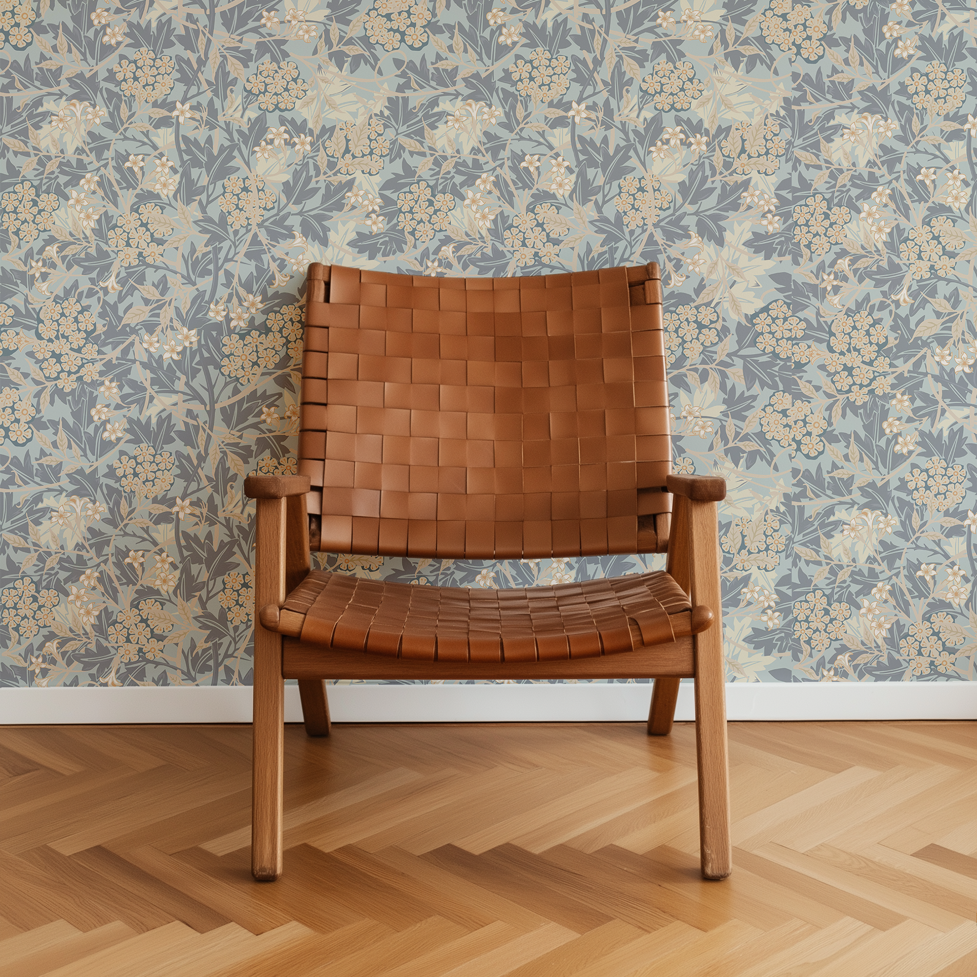 A mid-century modern wooden armchair with a woven tan leather seat and backrest, set against a blue and beige floral wallpaper and a light wood herringbone floor.