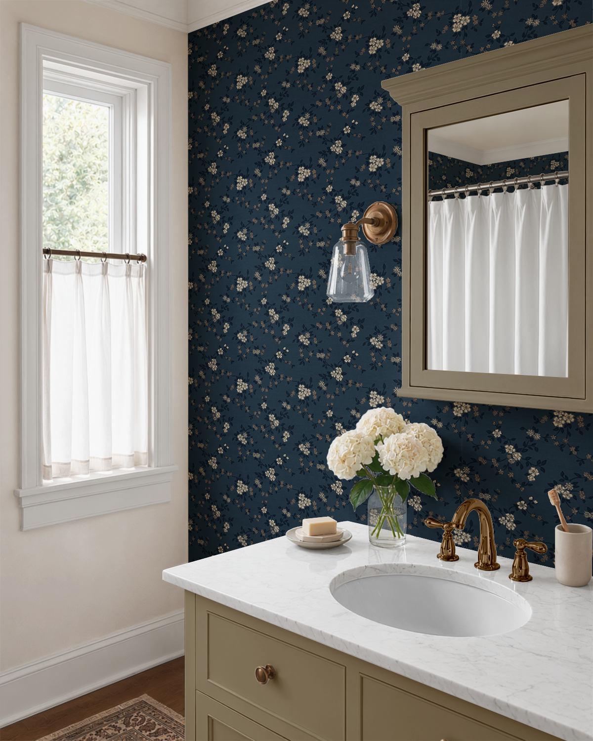 Navy blue floral wallpaper in a traditional bathroom with warm taupe vanity, brass fixtures and white marble countertop
