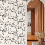 Abstract continuous line art faces wallpaper in a modern home interior with archway and warm accents.&quot;