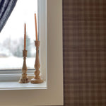 Minimalistic décor with wooden candlesticks on a windowsill, complemented by mini plaid wallpaper, creating a serene ambiance.