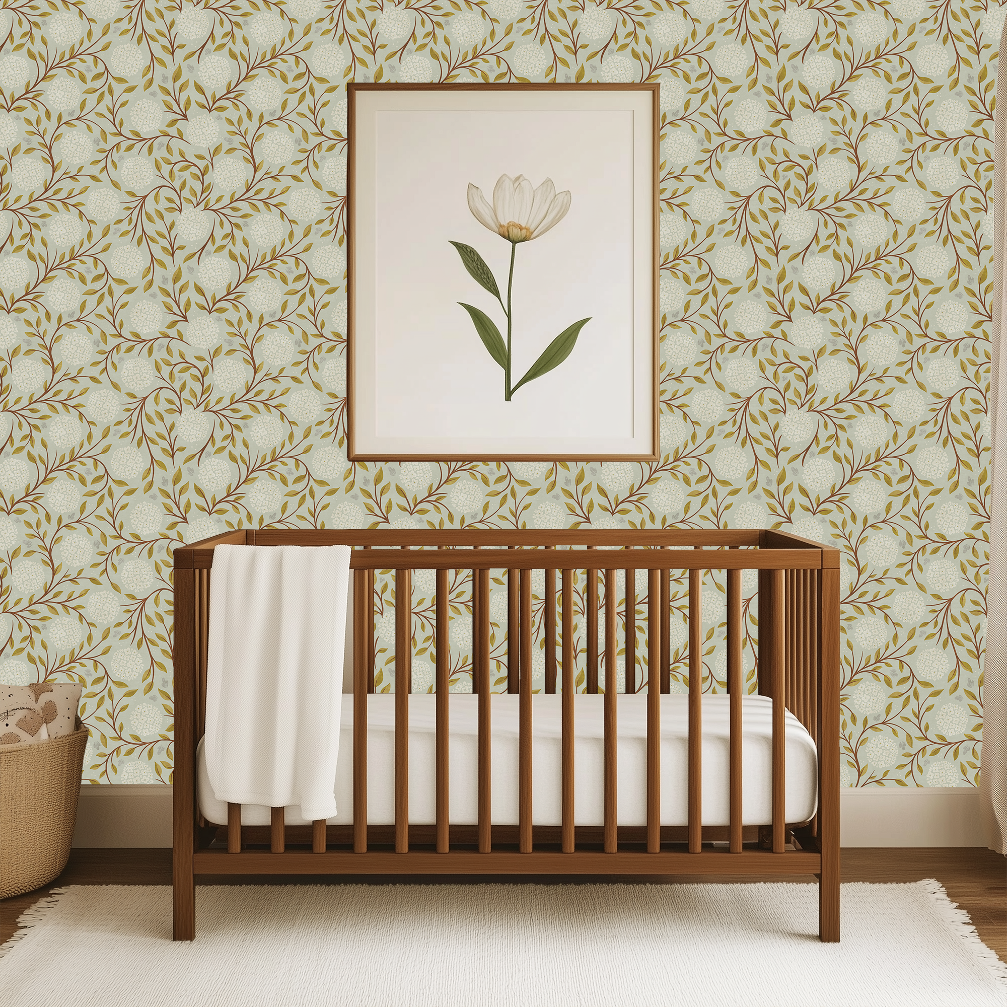 Wooden crib in a room with green and blue floral wallpaper and a framed picture of a flower.