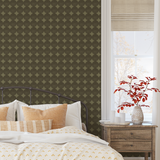 Bedroom with olive green dot wallpaper behind bed with neutral bedding and warm accents