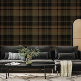 Olive and black tartan plaid wallpaper behind a charcoal sectional sofa and room divider in a modern interior.