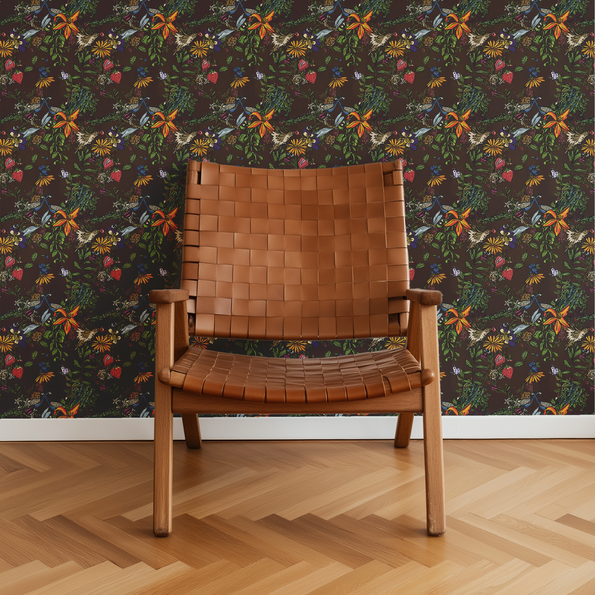 Peacock Espresso dark botanical wallpaper featuring colorful birds, orange lilies and wildflowers behind a tan woven leather accent chair.