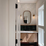 View through doorway showing beige zellige tile wallpaper above bathroom vanity with mirror and moody green tile contrast