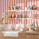 Colorful kitchen with Taffy stripe wallpaper behind open shelving and mugs
