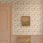 Playful shapes wallpaper in abstract retro tones of terracotta, beige, olive green, and blue, styled in a classic entryway with pink wainscoting