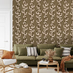 Snowberry Trail wallpaper installed behind a green sofa, highlighting the vertical botanical stripe design.