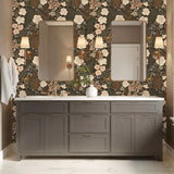 Stillwood floral wallpaper installed behind a bathroom vanity with brass sconces and neutral cabinetry