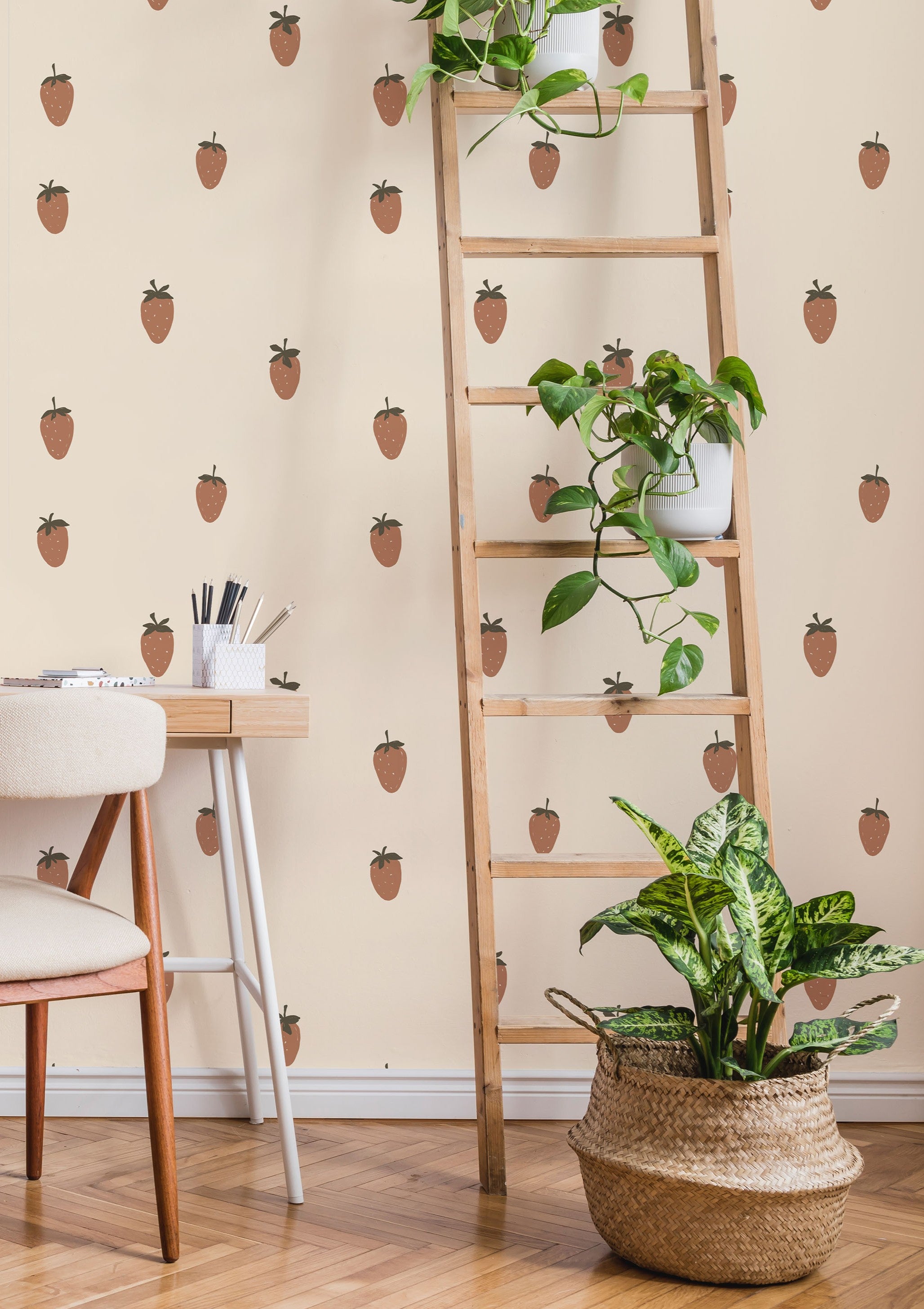 Strawberry wallpaper styled in a room with a wooden ladder shelf, trailing plants, and a woven basket planter