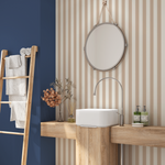 Sandstone beige and cream stripe wallpaper in a modern bathroom with wood vanity and round mirror