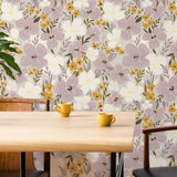 Floral wallpaper with purple and yellow flowers on a wall behind a wooden table with yellow cups.