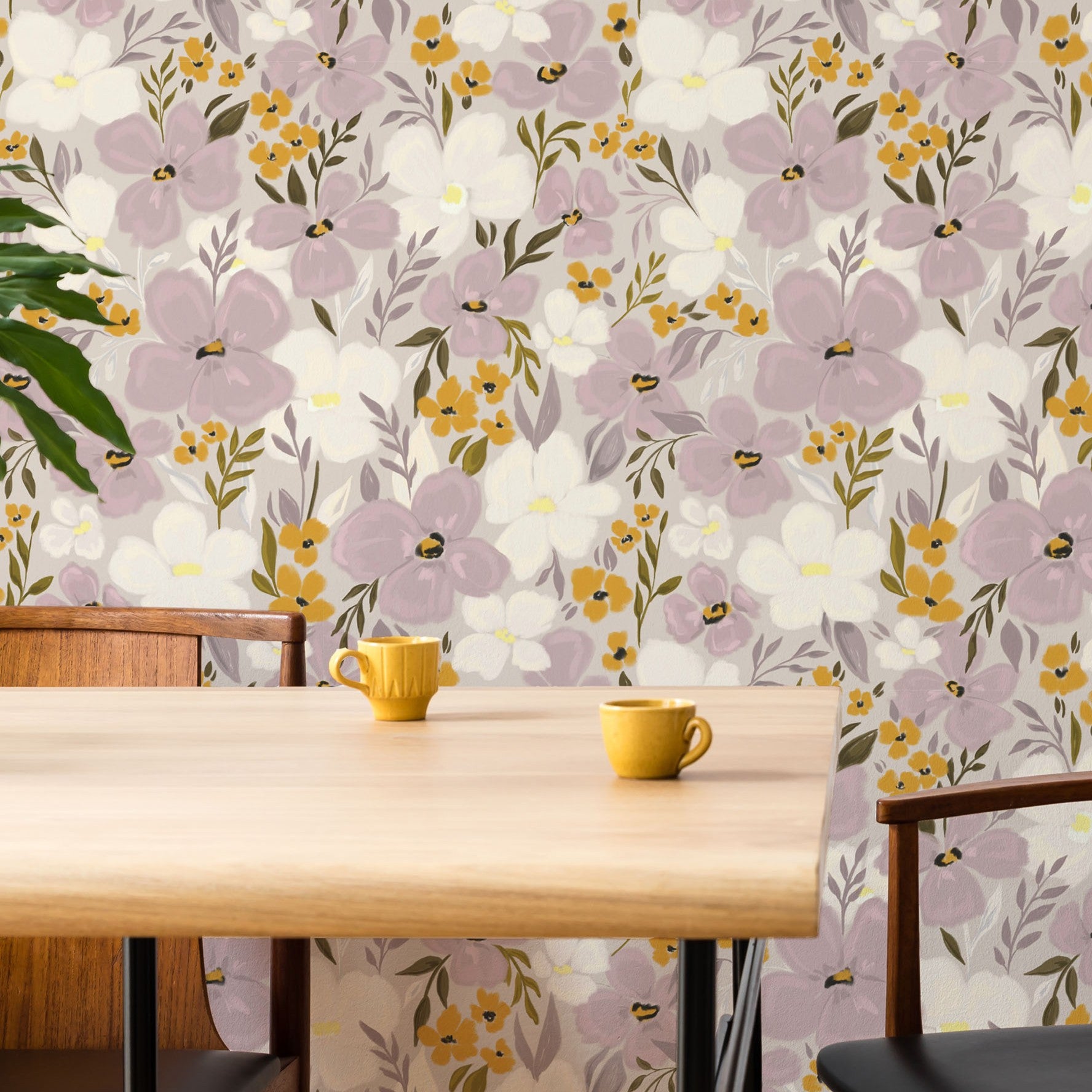 Floral wallpaper with purple and yellow flowers on a wall behind a wooden table with yellow cups.