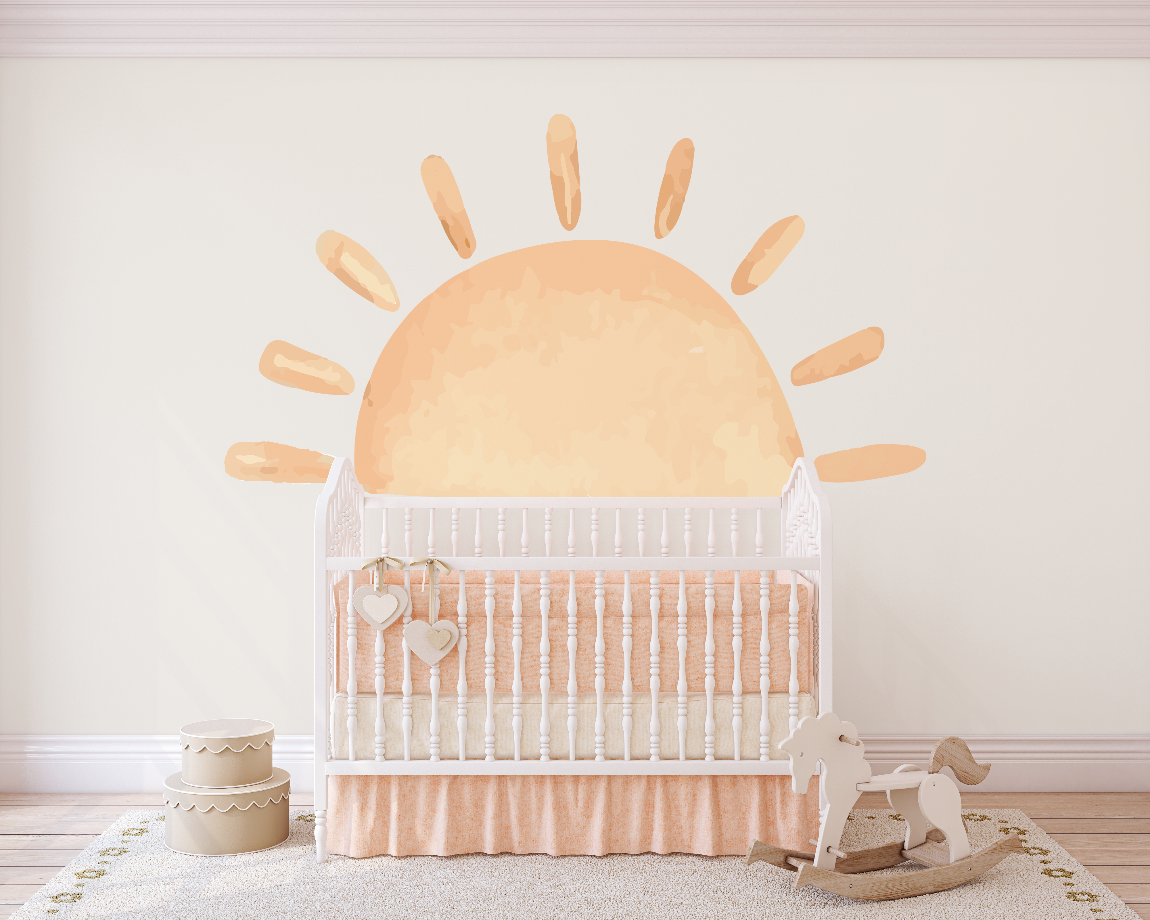 White crib in a nursery with a sunshine wall sticker, rocking horse beside.