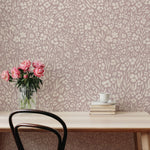 Desk with flowers and books against a floral wallpapered wall