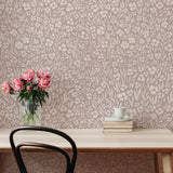 Desk with flowers and books against a floral wallpapered wall