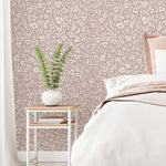 Bedroom with purple floral wallpaper, a bed, and a side table with a plant.