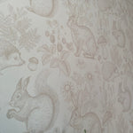 Close-up of a neutral nursery wallpaper depicting various woodland animals like rabbits and squirrels in a detailed beige sketch style.